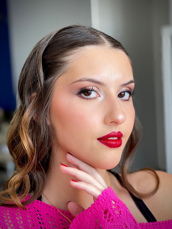 Jovem com ondas laterais no cabelo, olhos esfumados em tons quentes e batom vermelho