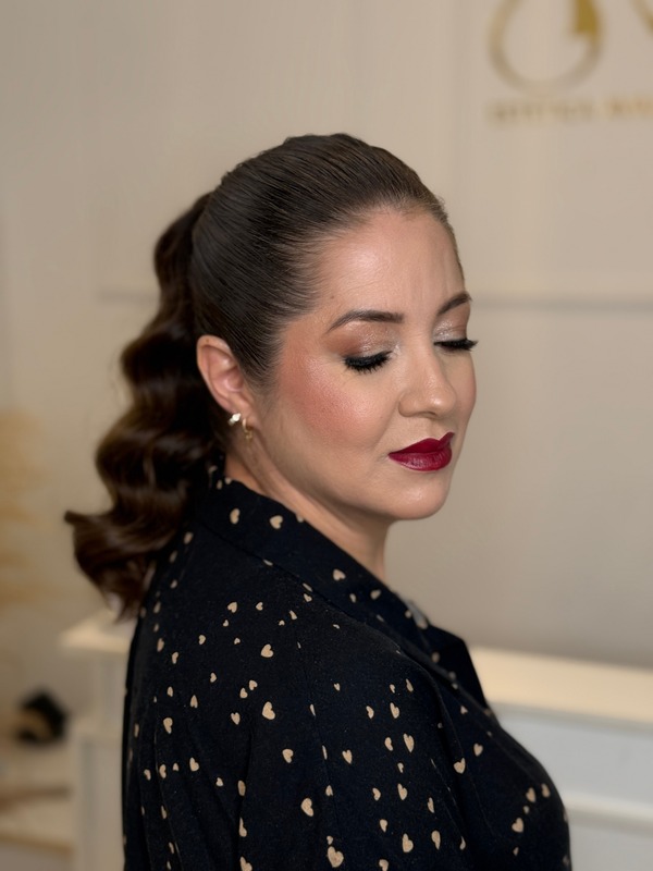 Mulher de perfil com rabo de cavalo ondulado, olhos dourados e batom vinho